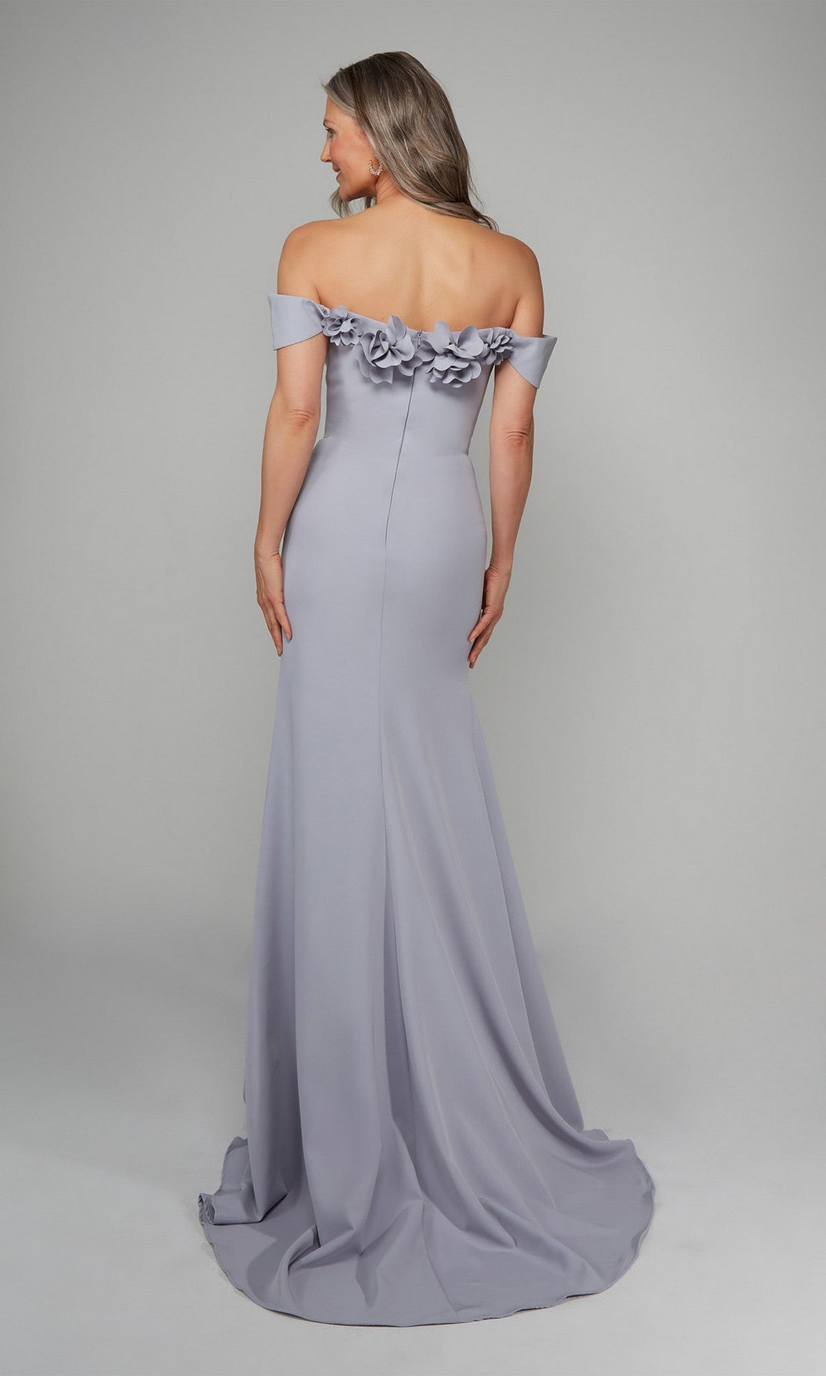 A woman faces away, wearing the Alyce 7062 long formal dress in lavender with off-the-shoulder styling and 3D floral accents at the neckline—a perfect choice for evening events.